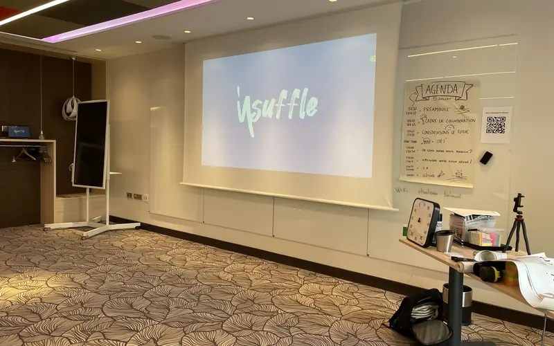 Salle de séminaire installée avant l’arrivée de l’équipe, écran Insuffle allumé