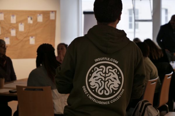 Facilitateur Insuffle de dos face à une équipe en séminaire